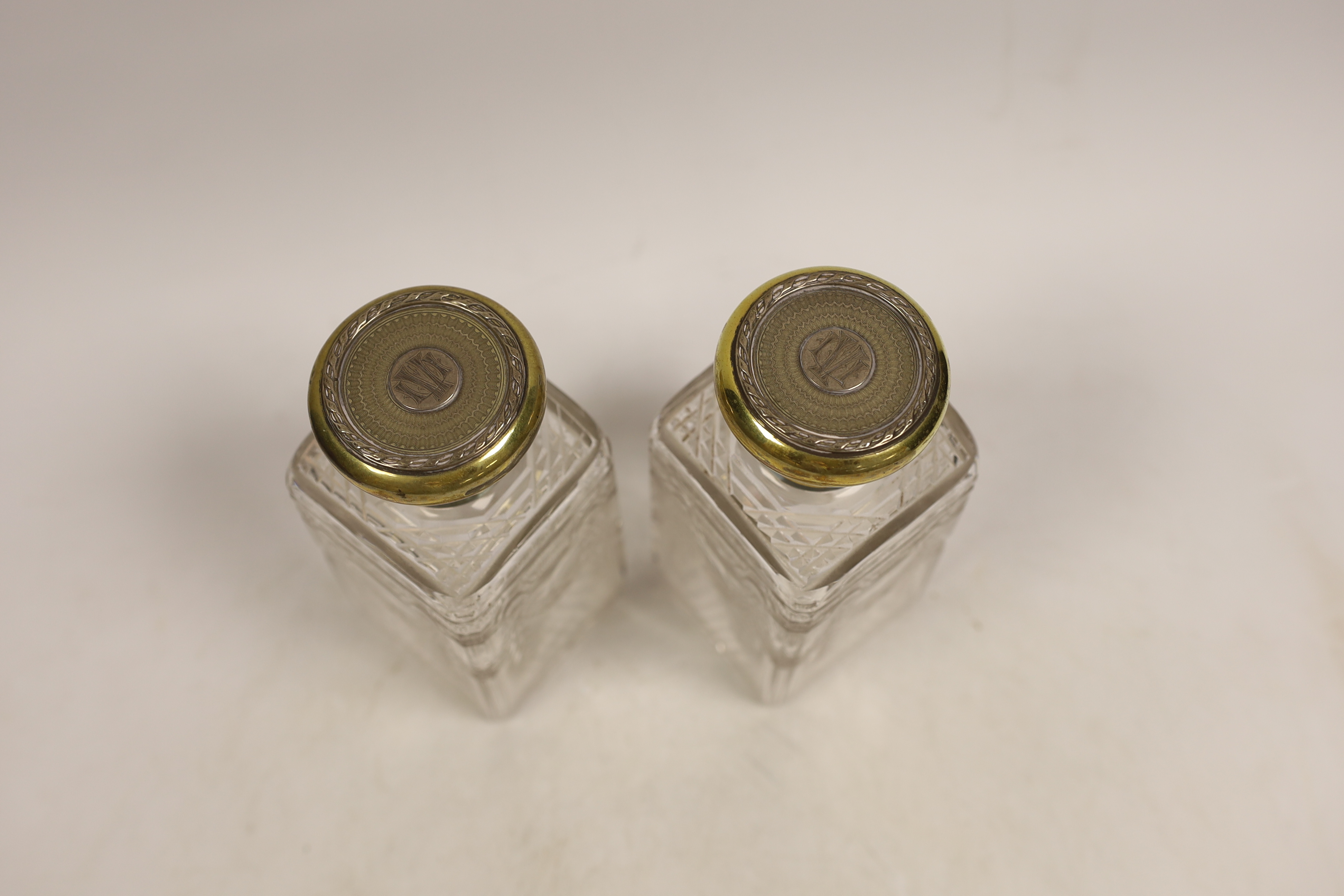 A pair of George V silver gilt mounted cut and etched glass square scent bottles and stoppers, Goldsmiths & Silversmiths Co Ltd, London, 1911, 15cm.